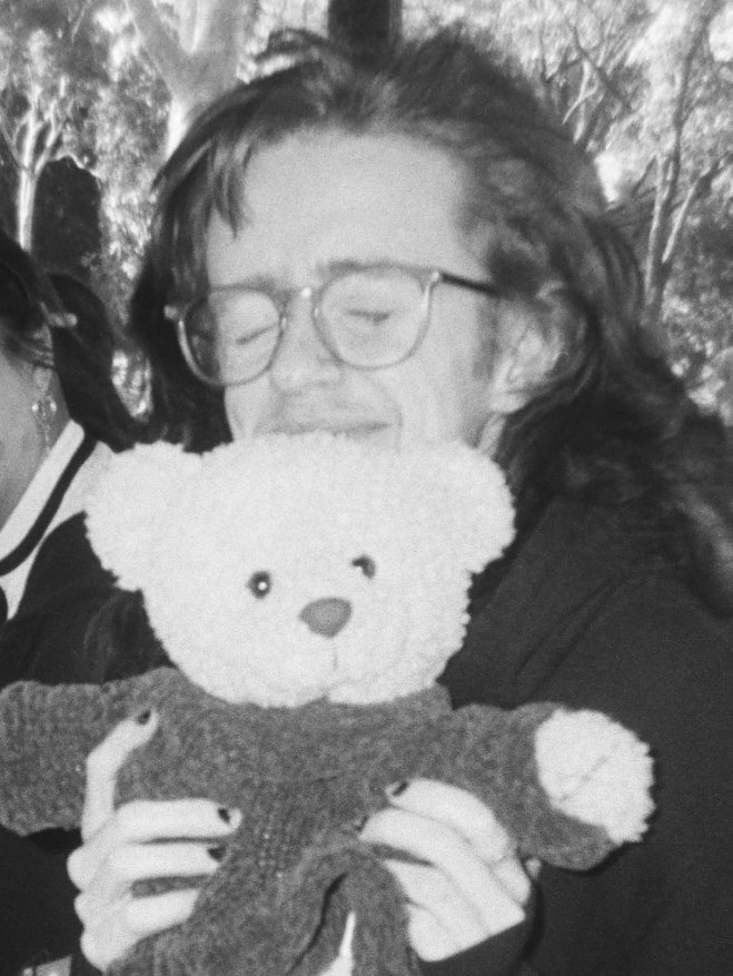 black and white photo of ezran holding a bear backpack and smiling